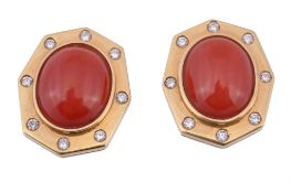 A pair of coral and diamond ear clips, the central oval cabochon coral (Corallium Rubrum) in a