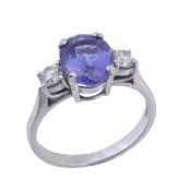 A tanzanite and diamond three stone ring, the oval cut tanzanite flanked  by two brilliant cut