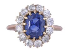 A sapphire and diamond cluster ring, the central oval mixed cut sapphire claw set above a surround