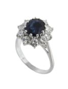 A sapphire and diamond ring, the central oval cut sapphire, claw set within a surround of brilliant