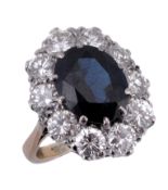 A sapphire and diamond cluster ring, the central claw set oval cut sapphire, within a surround of