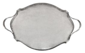 An Arts and Crafts hammered silver shaped oval twin handled tray by Omar Ramsden, London 1937,