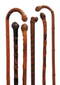 A Japanese finely carved and stained wood walking stick, early 20th century, the grip modelled as a