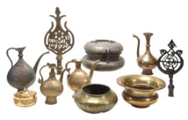 A collection of eight Islamic metal objects including four ewers rising from spreading feet through