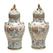 A pair of Chinese famille rose lidded jars of baluster shape decorated with panels depicting court