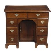 A George III oak kneehole desk, circa 1780, the rectangular top with re-entrant front corners, above