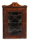 A George III mahogany and satinwood corner cupboard, circa 1800, with a tablet inset crest above