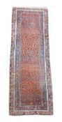 A Shiraz runner, the madder field decorated with a geometric design, within polychrome borders,