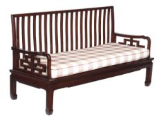 A Chinese hardwood settle, 20th century, with slatted back, pierced open arms, solid seat with loose