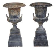 A pair of cast iron twin handled garden urns, of Campana form, each with a flared rim above a