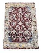 An Agra rug, the maroon field decorating with stylised foliate vines, boteh and within a