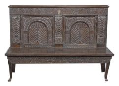 A carved oak settle with crewel work cushion, 17th century, the rectangular back with carved