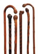 A Japanese finely carved and stained wood walking stick, early 20th century, the grip modelled as