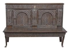 A carved oak settle with crewel work cushion, 17th century, the rectangular back with carved frieze