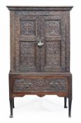 An oak cupboard on stand, mid 18th century and later, the moulded cornice above a pair of twin