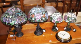 A pair of patinated metal and coloured glass table lamps in the style of Tiffany, together with two