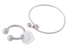 A silver bangle by Tiffany & Co., the polished bangle with a heart to each...  A silver bangle by