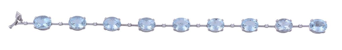 An aquamarine and diamond line bracelet, set along the line with oval shaped...  An aquamarine and