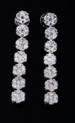 A pair of diamond ear pendants, each composed of a row of seven brilliant...  A pair of diamond ear