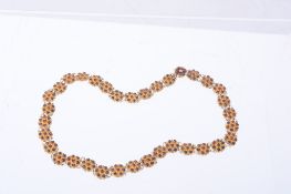 A garnet necklace, composed of hexafoil links each set with a cluster of...  A garnet necklace,