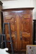 A large19th century Normandy cherrywood armoire with moulded cornice and panelled doors raised on