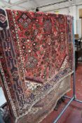 A Shiraz rug decorated with geometric motifs on a red ground 222 x 127cm