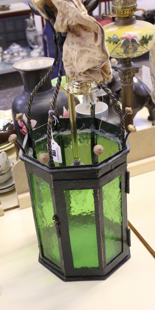 An octagonal wrought iron hanging lantern with green glass panels, 57cm high