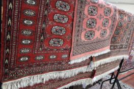 A red ground Bokhara rug 146 x 92cm, together with two further rugs (3) Best Bid