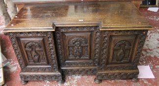 A Victorian inverted breakfront carved oak sideboard each panelled door profusely decorated with