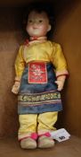A Chinese doll, with composition head and real hair wig, painted features, dressed in a silk