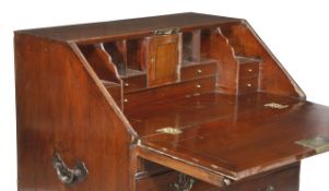 A George III hardwood bureau, circa 1790, the fall opening to an arrangement of drawers and pigeon