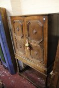 An early 18th century style oak cabinet with geometric panelled doors on stand with turned legs