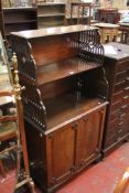 A George III style mahogany cabinet with graduated shelves on fretwork supports and cupboard below