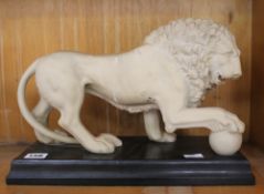 A decorative model of a standing lion on black plinth base; approximately 24cm high x 35cm long