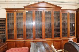 A George III style mahogany breakfront bookcase with arched pediment and dentil moulded cornice,