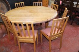 An oak circular table 75cm high, 146cm diameter and a set of eight dining chairs each with vertical