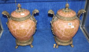 A pair of brass mounted ovoid ceramic vases and covers, gilt decorated on a pink ground; 43cm high