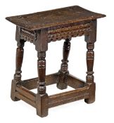 A James I oak joint stool, circa 1610, the solid rectangular seat with moulded edge above a carved