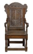 A Charles II oak panel back armchair, circa 1660, the cartouche shaped back carved profusely with