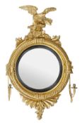 A George III carved giltwood convex girandole mirror, circa 1800, the circular plate within an