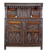 A Charles II oak press cupboard, circa 1660, carved throughout with stylised foliage and lozenge