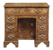 A George II walnut kneehole desk, circa 1735, the rectangular quarter veneered and featherbanded top