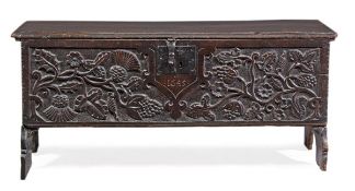 A Charles I elm plank chest, circa 1645, the hinged lid above a profusely carved front depicting