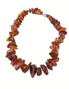 An amber necklace, the graduated amber pieces, on a knotted string, 63.5cm long An amber necklace,