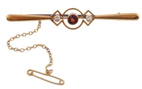 A garnet and half pearl bar brooch, the central circular cut garnet between... A garnet and half