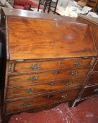 A George III mahogany bureau with a fitted interior and four long drawers with a shaped apron and