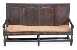 A George II oak panelled back settle, circa 1740, the quadruple panelled back, downswept open arms,