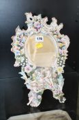 A Dresden table mirror decorated with encrusted flowers and two young figures; approximately 33cm