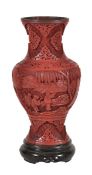 A Chinese cinnabar lacquer vase decorated with figures amid a mountainous setting, 24cm high