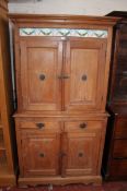 A late 19th Century pine cupboard with tile frieze, the fielded panelled cupboards enclosing
